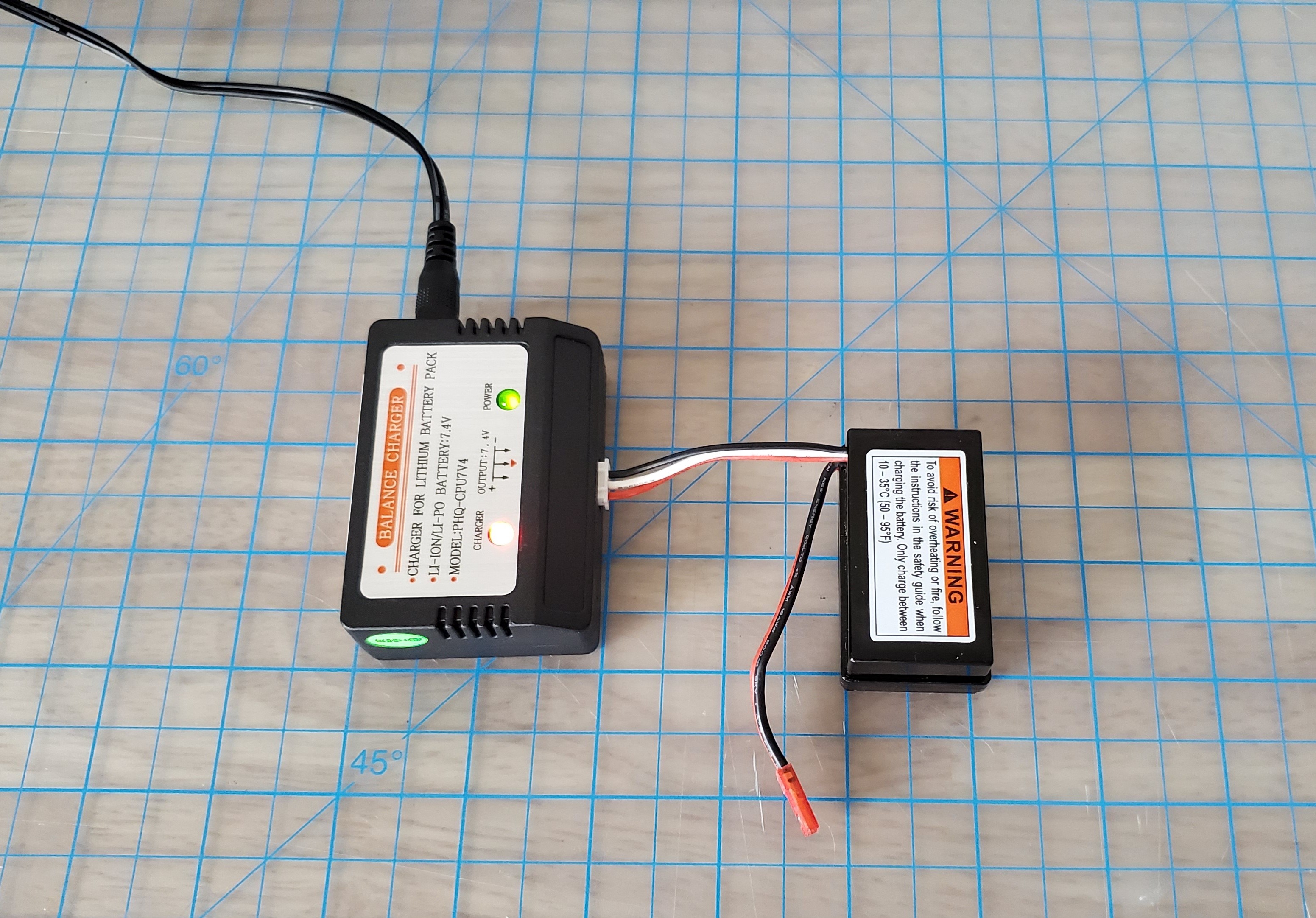 Image: The vehicle's drive module battery is connected to the battery charger, which is plugged into a power outlet.
