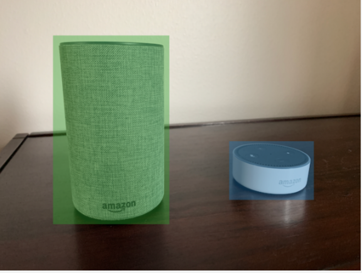 木质表面上有两个 Amazon 智能扬声器,一个带有绿色边界框,另一个带有蓝色边界框。